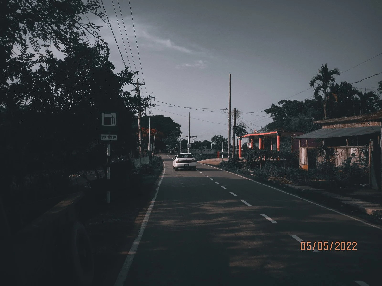 An empty highway running past a petrol station in failing light