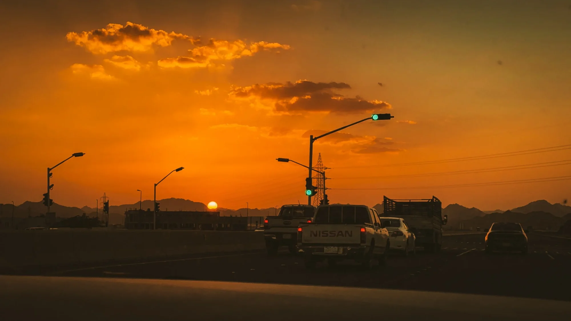 Traffic at a junction with the sun going down behind bare mountains