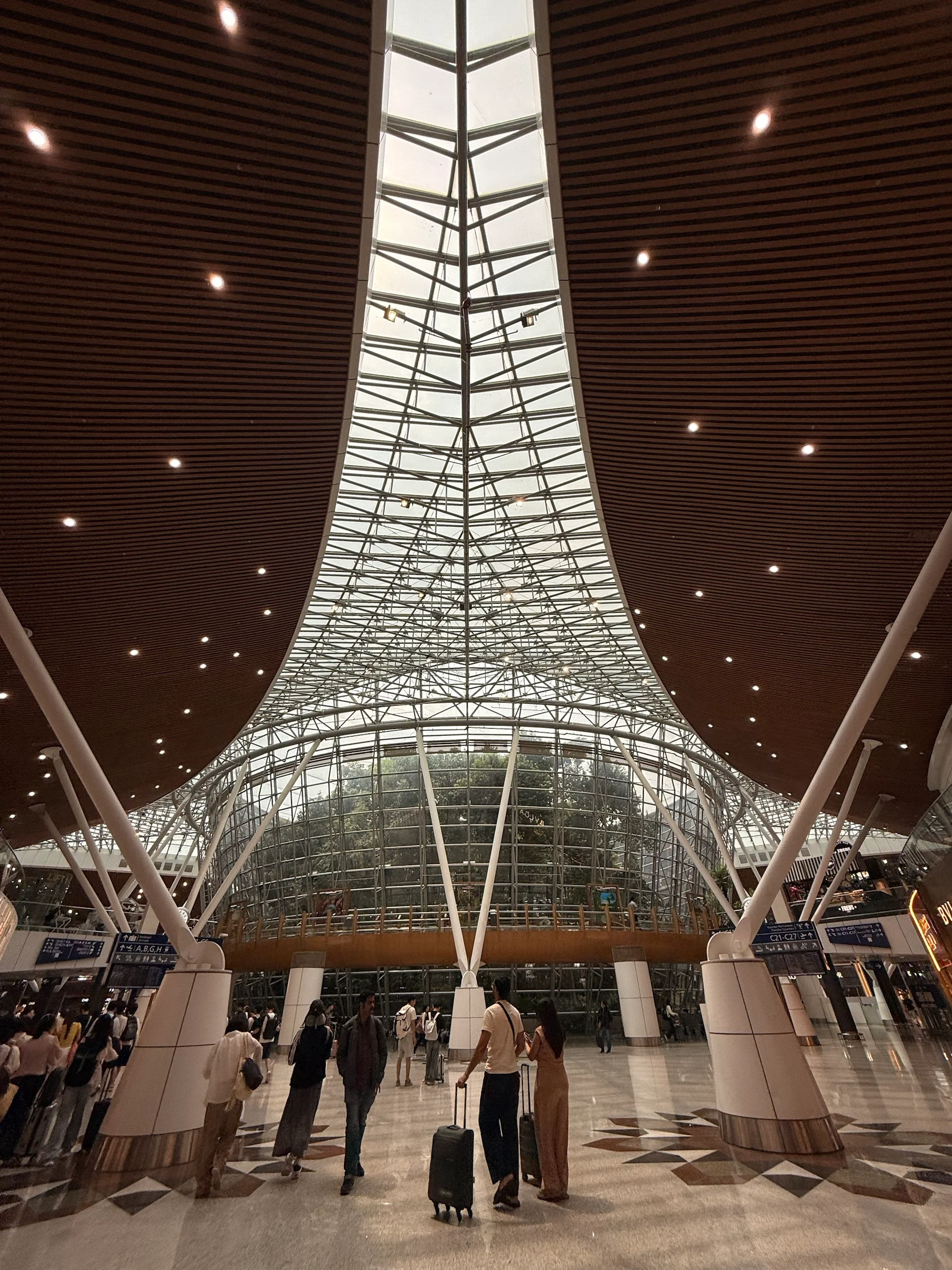 The glass and steel atrium of Kuala Lumpur International Airport with travellers below
