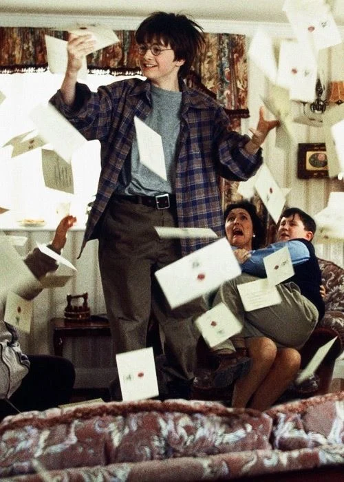Letters flying around a sitting room while a boy laughs