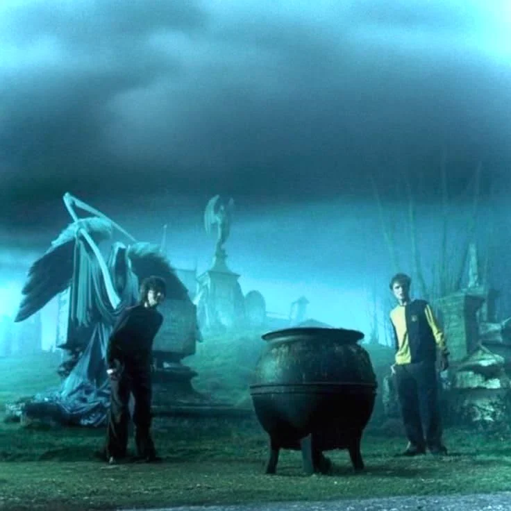 Two boys and a cauldron in a graveyard under a black sky