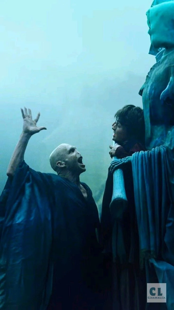Voldemort raising a hand while Harry is bound to a headstone