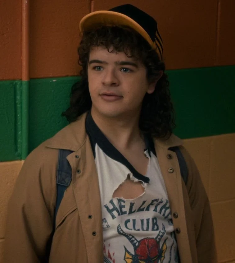 Dustin in a cap and a torn Hellfire Club shirt