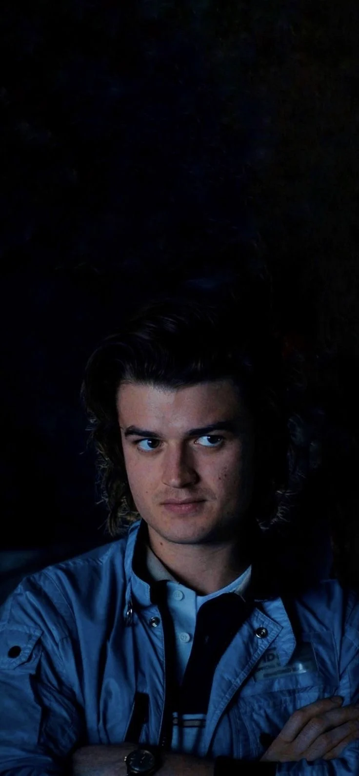 Steve Harrington in a dark room, lit from one side